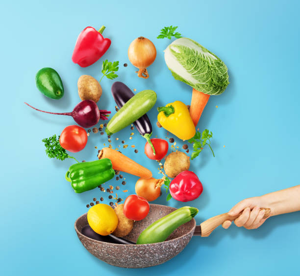 istock Cooking concept. Vegetables and bacon are falling on a pan isolated on white background. Healthy food. 1248166766