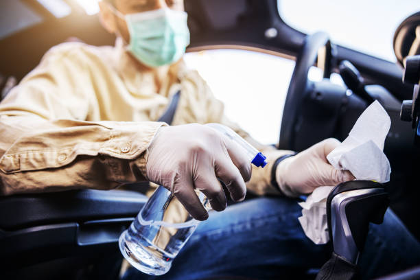 Man in protective suit with mask disinfecting inside car, wipe clean surfaces that are frequently touched, prevent infection of Covid-19 virus coronavirus,contamination of germs or bacteria. Infection prevention and control of viruses. hombre en traje protector con mascarilla desinfectante dentro del coche, limpiar las superficies que se tocan con frecuencia, prevenir la infección del coronavirus del virus covid-19, contaminación de gérmenes o bacterias. prevención y control de infec