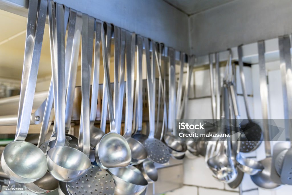 close up view of many soup ladles hanging from a wall rack in a restaurant kitchen A close up view of many soup ladles hanging from a wall rack in a restaurant kitchen Clean Stock Photo