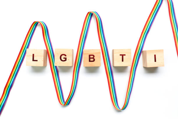 Ribbon with the rainbow flag between wooden blocks forming the word LGBTI on a white background stock photo