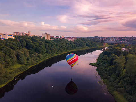 Hot air balloon is flying at sunrise or sunset. Aerial drone view