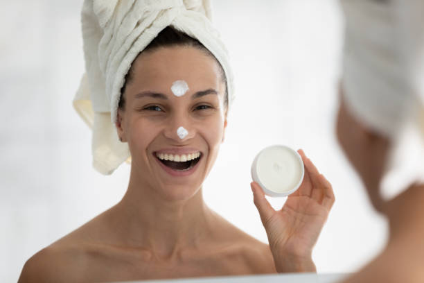 istock Head shot mirror reflection smiling woman holding face cream jar 1248172050