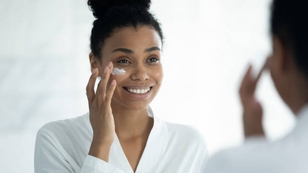 istock Mirror reflection smiling African American woman applying moisturizing cream 1248172130