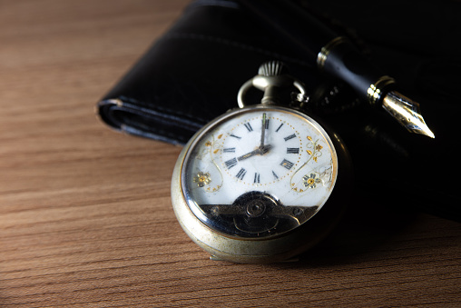A broken antique pocket watch on old weathered wood.