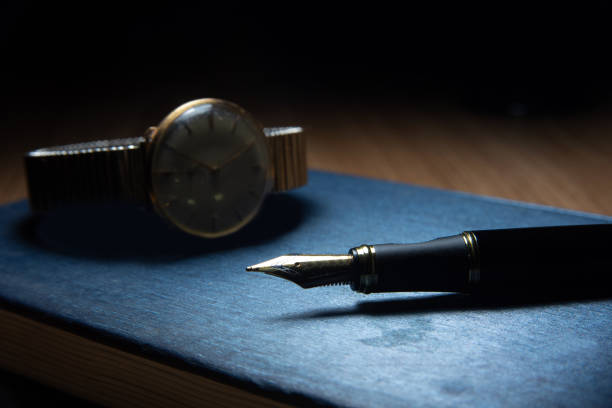 istock Fountain pen and antique watch in underexposed light 1248176288