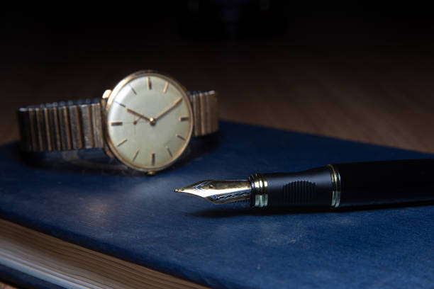 istock Fountain pen and antique watch in underexposed light 1248176421