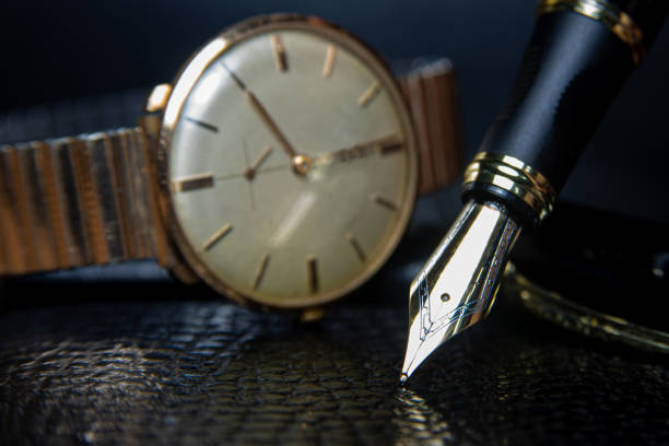 istock Fountain pen and antique watch in underexposed light 1248177004