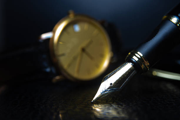 istock Fountain pen and antique watch in underexposed light 1248177012