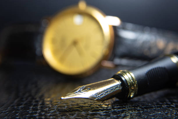 istock Fountain pen and antique watch in underexposed light 1248177020