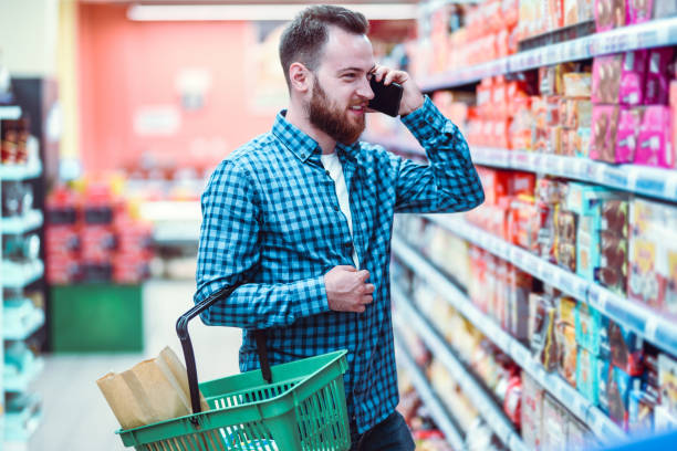 istock Handsome Male Using Phone While Shopping Groceries In Supermarket 1248177219