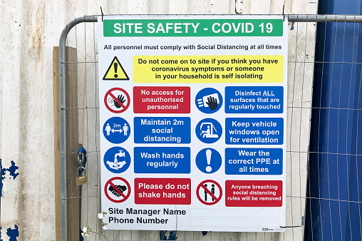 Staffordshire, England, UK - 8th June 2020: A sign displaying COVID-19 site safety information at the entrance to a construction site. COVID-19 is a new illness that can affect your lungs and airways.