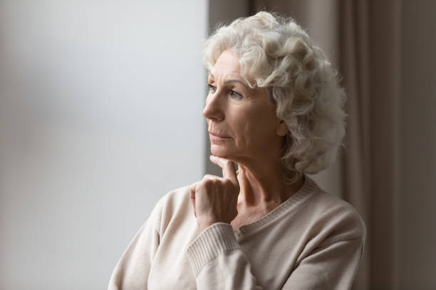 istock Sad senior woman look in window thinking 1248182173