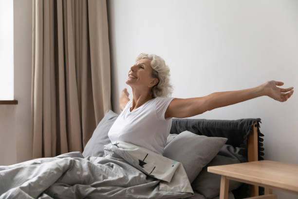 istock Optimistic elderly woman stretch awaken in home bed 1248182226