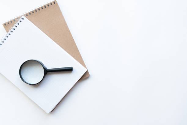istock Workplace with notebooks and magnifying glass on the left on light white backround. Copy space. Top view. Concept business. 1248182750