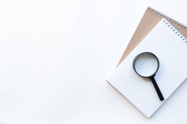 istock Workplace with notebooks and magnifying glass on the right on light white backround. Copy space. Top view. Concept business. 1248182754