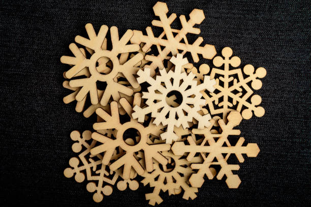 istock Many light brown wooden snowflakes on dark grey textile material background, displayed centred, top view with space for text around, flat lay with laser cut wooden objects 1248184325