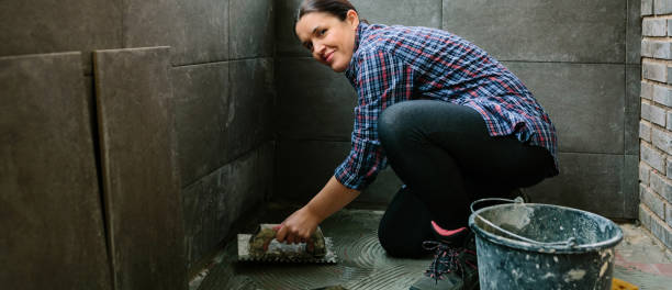 Female mason laying a new tile floor Smiling female mason laying a new tile floor on a terrace mason craftsperson stock pictures, royalty-free photos & images