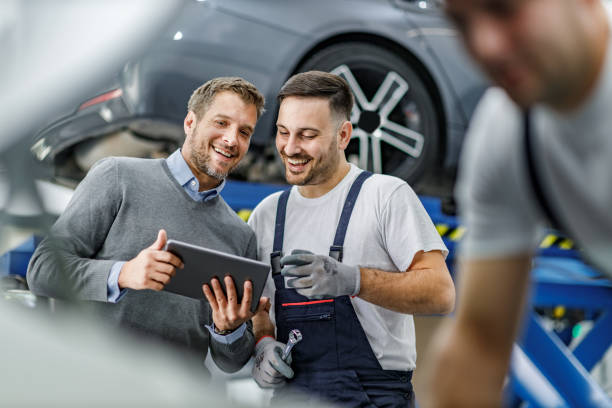 cliente felice e meccanico automatico che utilizza il touchpad in officina. - customer auto repair shop car mechanic foto e immagini stock