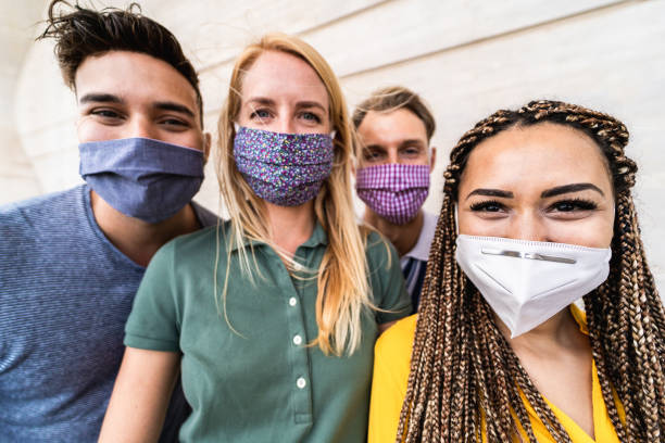 istock Group of young people taking selfie with phone camera while wearing protective masks - Happy friends taking photos during coronavirus outbreak - Social distancing concept - Focus on right girl eyes 1248187117