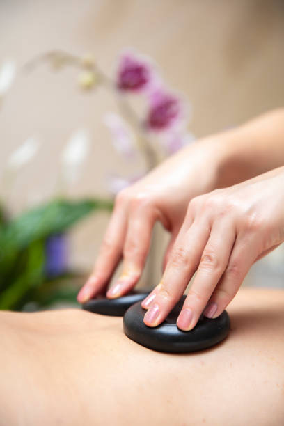 istock Massage therapist using hot lava stones during health spa relaxing stone therapy 1248187399