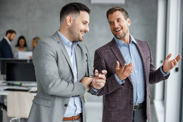 istock Happy male colleagues talking at corporate office. 1248189621