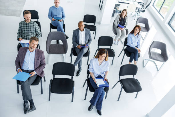 Social distancing at board room! High angle view of business people respecting social distancing during an education event in board room. business conference photos stock pictures, royalty-free photos & images