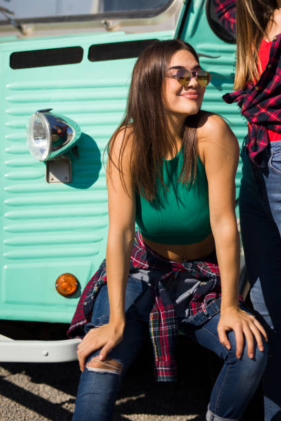 istock Smiling young women by the vintage minivan 1248194368