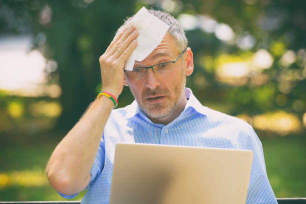 istock Man suffers from heat while working with laptop 1248196917