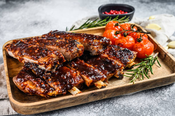 deliziose costolette alla brace condite con una salsa piccante e servite con pomodori al forno. sfondo grigio. vista dall'alto - sparerib foto e immagini stock