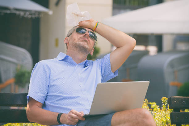 istock Man suffers from heat while working with laptop 1248197036