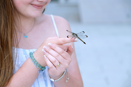 Teenage girl with a dragon fly on her finger