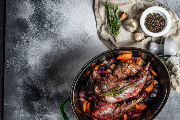 Roasted rabbit legs in pan with bulb of garlic and rosemary. Top view. Organic meat. Space for text Roasted rabbit legs in pan with bulb of garlic and rosemary. Top view. Organic meat. Space for text. rabbit game meat stock pictures, royalty-free photos & images