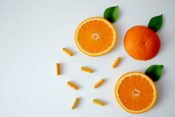 капсулы витамина с и ломтики апельсина - anti aging pill capsule vitamin pill стоковые фото и изображения