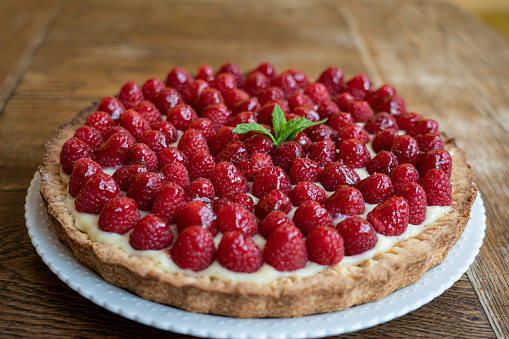 close up of an homemade crostata pie with cream and raspberry