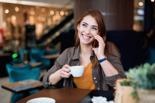 istock Beautiful young woman using her phone in coffee bar 1248202475