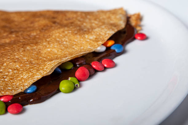 istock chocolate crepe with chocolate lentils and colored caramel. Isolated image 1248216369