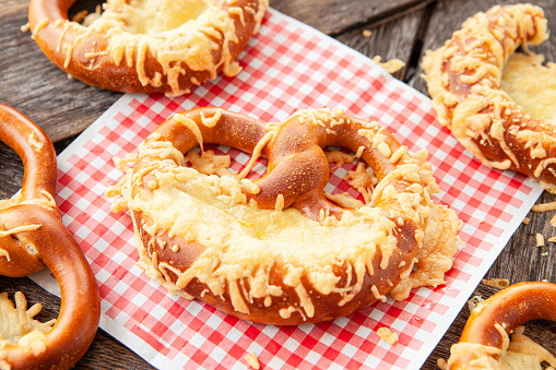 Delicious soft pretzels with cheese on a wooden background