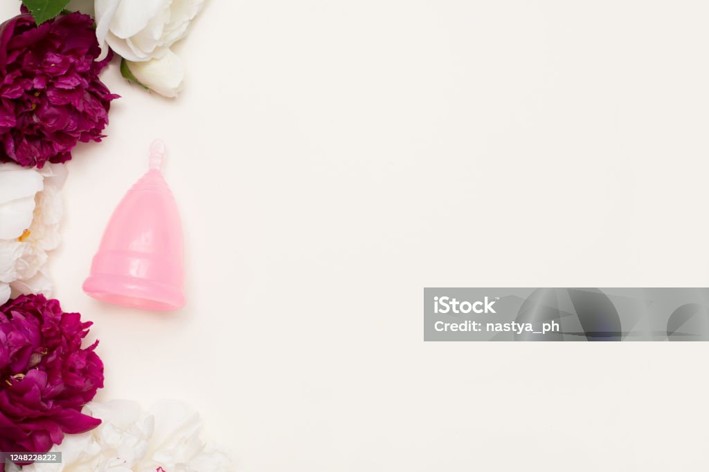 pink menstrual cup for women with flowers on light background. Ecological alternative to gaskets and tampons Rubber - Material Stock Photo
