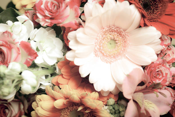 Bouquet of pink and yellow flowers in simple glass bottle