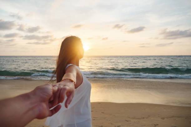istock Sunset at sea. Woman in a white blouse pulls a man's hand 1248231728