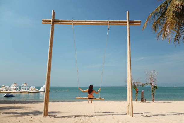 istock Woman on a swing at the beach 1248231732