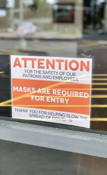 During the covid-19 outbreak in 2020, a masks are required for entry sign hangs on a retail store’s door
