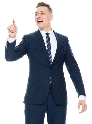 Portrait of aged 20-29 years old with short hair caucasian young male presenter standing in front of white background wearing businesswear who is cheerful who is pointing presenting