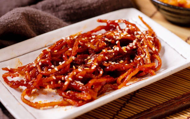 istock Seasoned dried shredded squid (ojingeochae muchim) with kimchi on wood table 1248237040