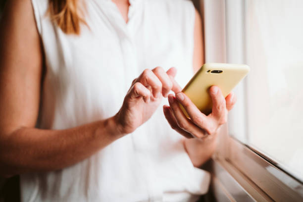 istock unrecognizable young woman at home using mobile phone by the window 1248240430