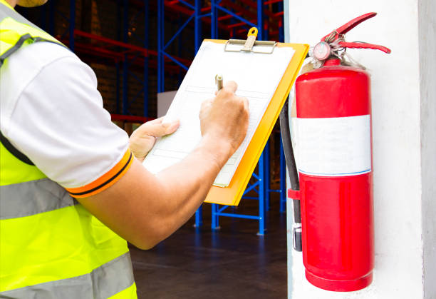 Engineer technician checking fire extinguisher writing on clipboard at warehouse Engineer technician checking fire extinguisher writing on clipboard at warehouse. Inspection Fire protection inside the building. fire inspection stock pictures, royalty-free photos & images