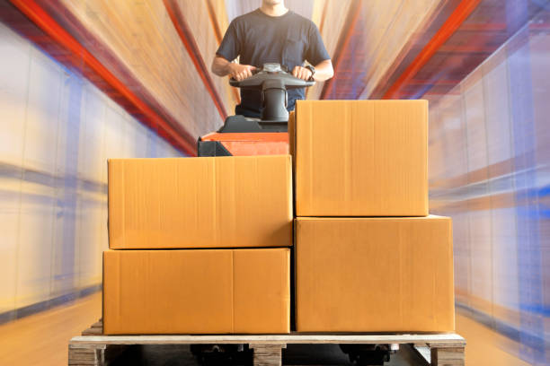 istock Warehouse worker driving electric forklift pallet jack unloading shipment boxes in the warehouse. 1248240523