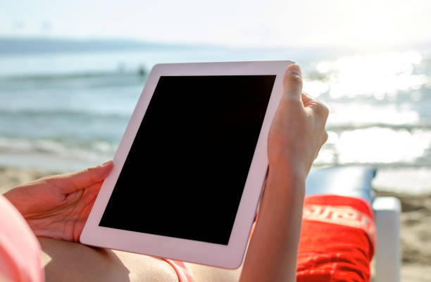 istock Vacation. Woman with a tablet pc or smartphone on the beach. 1248240611