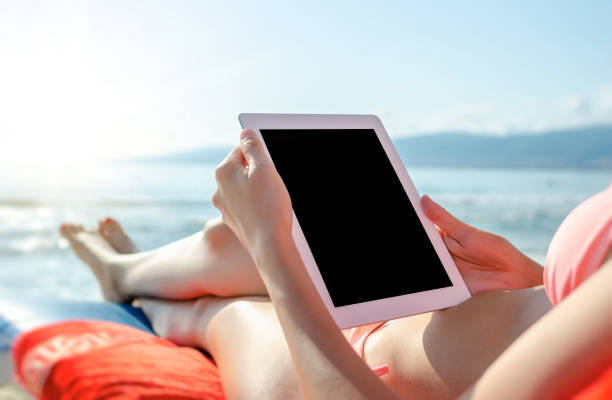istock Vacation. Woman with a tablet pc or smartphone on the beach. 1248240623