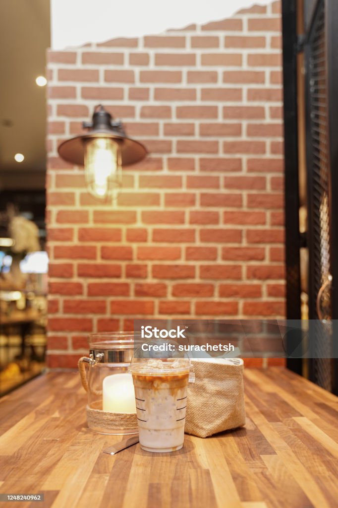 Take Away Latte With Brick Background On The Wood Table Stock Photo
